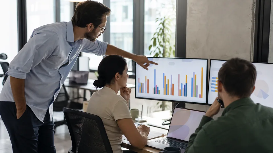 Analyst and manager reviewing charts together at a desk in a bright office