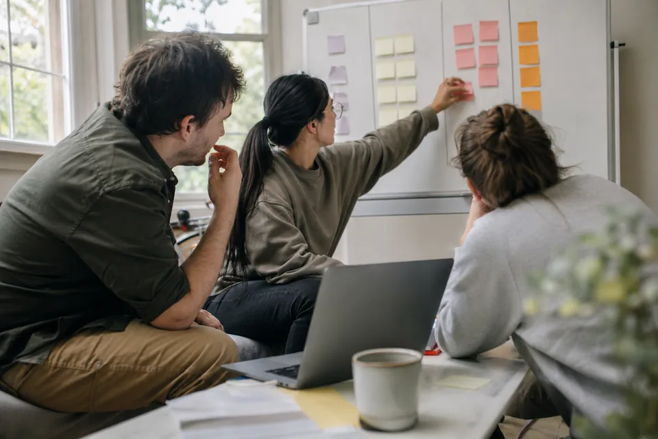 Operations team comparing BI vendor options on a whiteboard around a laptop
