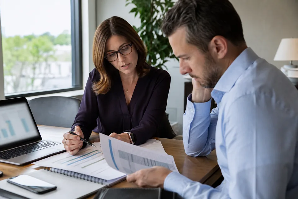 Finance director and data lead reviewing a BI software contract and annual budget at a conference table